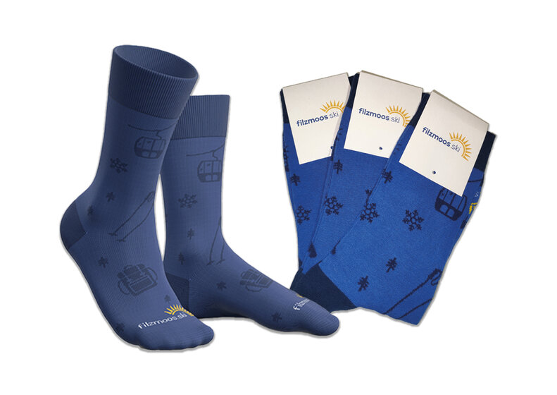 Blaue Filzmoos-Socken mit Skilift-, Ski- und Schneeflockenmotiven, vor hellem Hintergrund. | © Bergbahnen Filzmoos GmbH