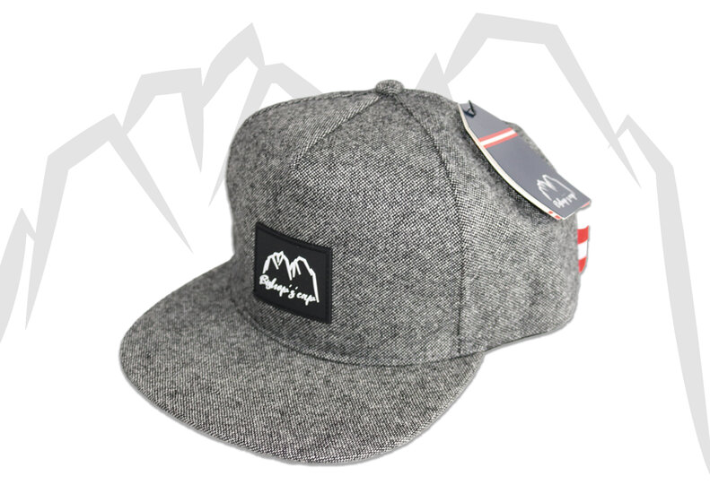 Dunkelgraue Snapback-Cap mit geradem Schirm und Berglogo, freigestellt vor hellem Hintergrund. | © Bergbahnen Filzmoos GmbH