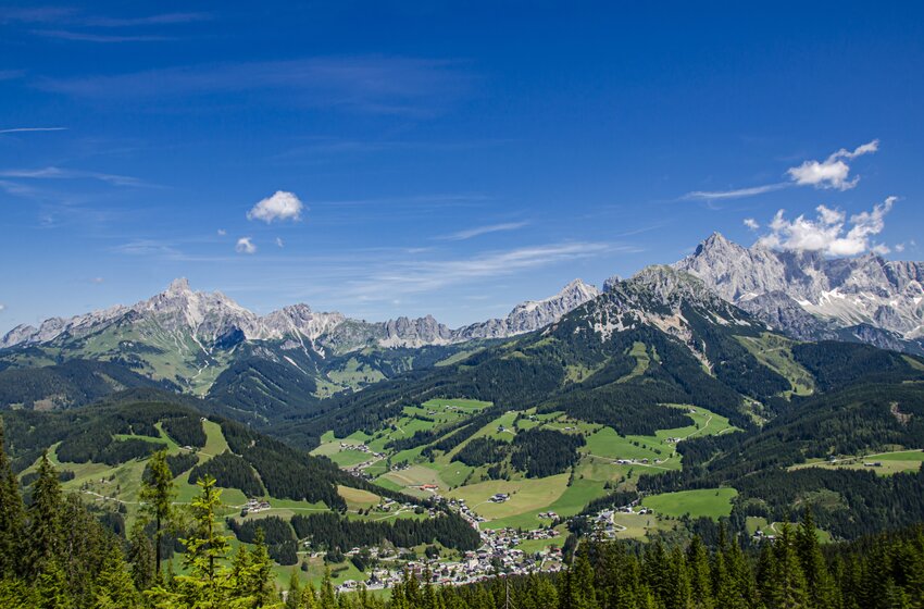 Wide valley with village, green meadows and forests before rugged Alps under clear blue sky in summer | © Bergbahnen Filzmoos GmbH