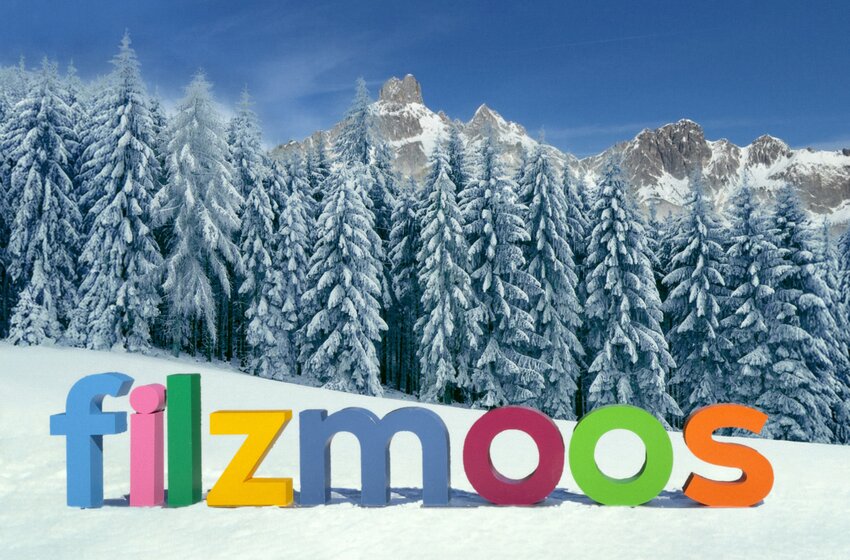 Colourful “Filzmoos” letters in snow with snowy fir trees and striking mountain peaks behind. | © Bergbahnen Filzmoos GmbH