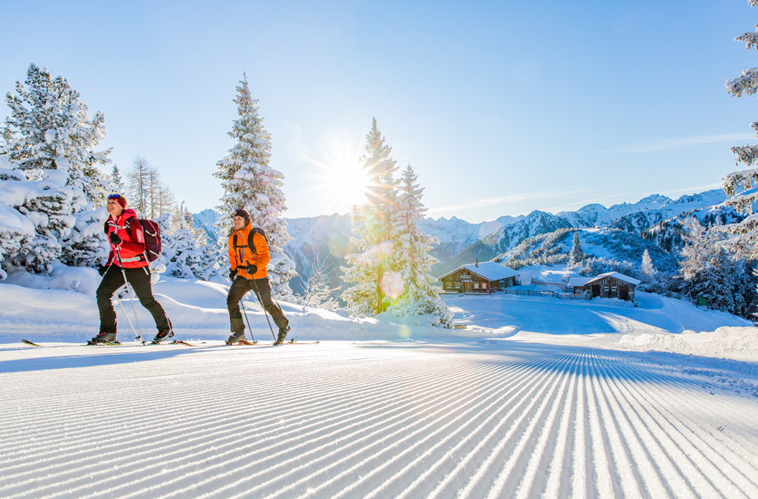 Ski tourers on groomed slope in a snowy alpine winter landscape | © Ski amadé GmbH Two ski tourers on a snowy piste in bright and clear alpine winter weather | © Ski amadé GmbH